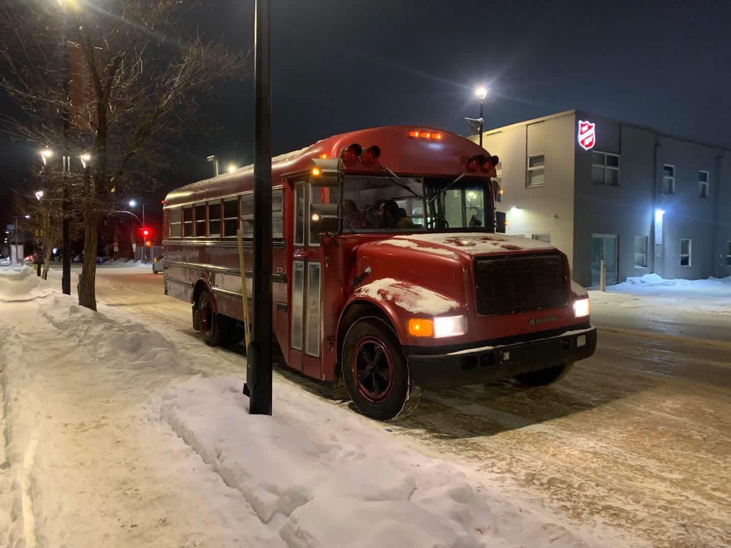 Bus parked on a snowy street at night